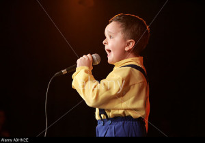 Singer kid boy 5 6 7 8 years old singing on a stage performance performing communicating microphone mike concert rehearsal feeli